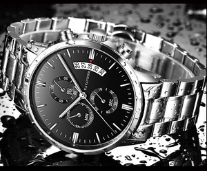 Macro shot of stainless steel watch with black dial and water droplets for waterproof display