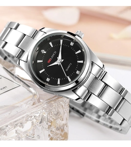 Close-up of black dial watch with sparkling diamond markers and silver stainless strap