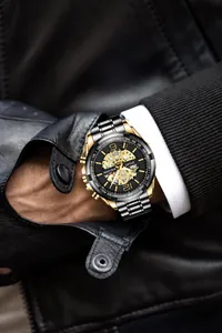 Dettaglio macro dell'orologio sportivo da uomo nero e oro con quadrante scheletrato al polso