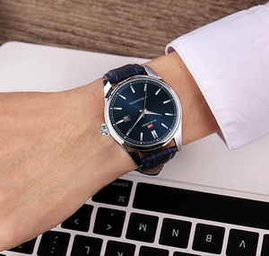 Gros plan d'une montre d'affaires à cadran bleu avec boîtier en acier au poignet