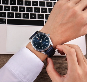 Gros plan d'une montre à cadran bleu brossé soleil avec guichet de date et bracelet en cuir