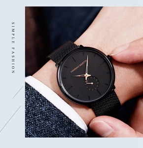 Men's black quartz watch with Milanese mesh strap shown on a navy suit sleeve