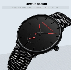 Macro shot of black minimalist watch face with red hands and metallic mesh strap