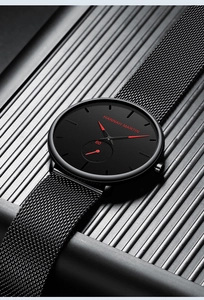 Macro shot of black mesh steel strap and red hands on a minimalist quartz watch