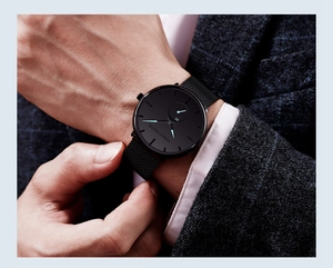 Macro shot of Hannah Martin black quartz watch with cyan needles on a male wrist