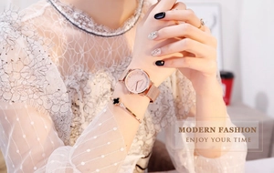 Gros plan sur la montre à cadran étoilé or rose et le bracelet trèfle au poignet