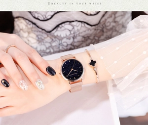 Détail d'une montre femme en maille or rose avec un cadran effet ciel étoilé bleu foncé
