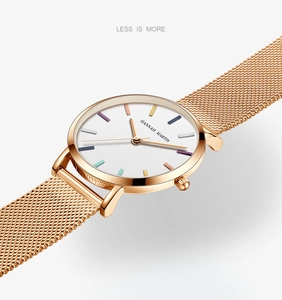 Detail shot of thin rose gold watch case and Milanese mesh strap with minimalist markers