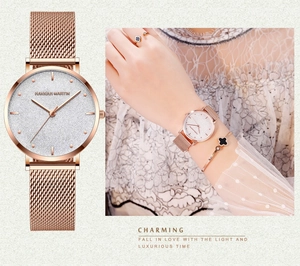 Détail de montre maille or rose avec cadran scintillant et ensemble bijoux trèfle