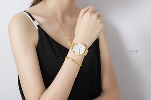 Detail of gold women's watch with colorful dial markers and mesh band on model's wrist