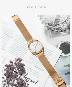 Close-up of golden stainless steel mesh strap and watch dial with multicolor indices