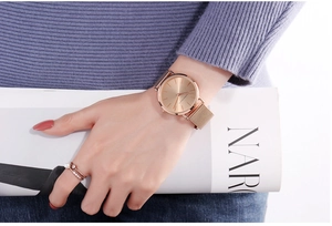 Close-up of minimalist rose gold watch with mesh strap and elegant pearl ring