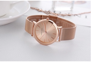 Detailed close-up of rose gold minimalist watch with Milanese mesh strap on elegant leather