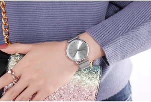 Close-up of woman wearing a silver quartz watch with mesh band and a glitter handbag
