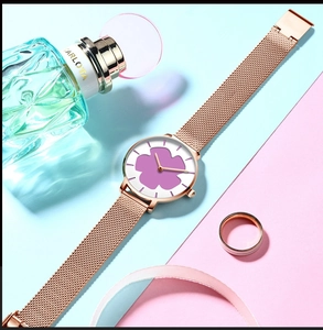 Gros plan d'une montre à bracelet maille or rose avec cadran tournesol violet sur fond pastel