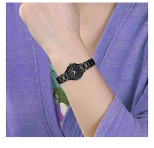 Minimalist all-black quartz watch with stainless steel strap worn on a purple sleeve