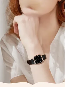 Detail of elegant square ladies quartz watch with black leather strap on female wrist