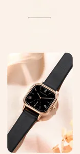 Detail of elegant square rose gold watch with black leather strap on silk fabric