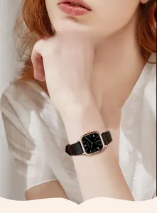 Elegant rose gold square watch with black leather strap worn on a woman's wrist
