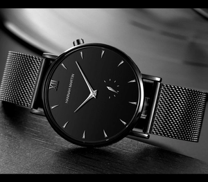 Close-up of black mesh strap and matte watch face with silver hands and Roman numerals