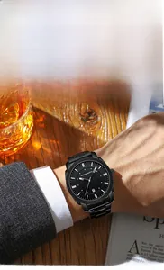 Gros plan d'une montre d'affaires en acier noir avec dateur sur un bureau en bois