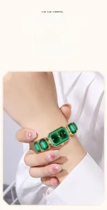 Dettaglio di elegante orologio al quarzo dorato con cristalli verdi e quadrante a raggio di sole