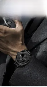 Close-up of a men's black stainless steel watch with date display on a grey suit sleeve