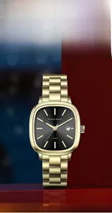 Détail macro de montre carrée Hannah Martin dorée avec cadran noir et guichet de date