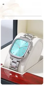 Detailed close-up of a silver square watch with a turquoise blue dial in a gift box