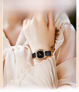 Elegante eckige Damenuhr mit schwarzem Lederarmband und Goldgehäuse am Handgelenk