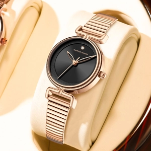 Elegant rose gold women's watch with black dial and minimalist elastic strap on a leather pillow