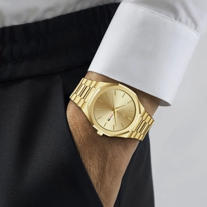 Men's minimalist gold stainless steel quartz watch with day-date display on wrist