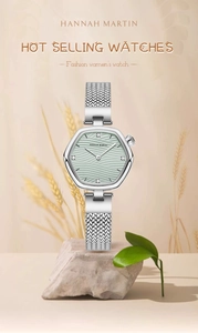 Detail of a thin hexagonal women's watch with green dial and silver mesh strap on rock