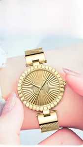 Close-up of golden quartz watch with sunray dial and stainless steel mesh strap