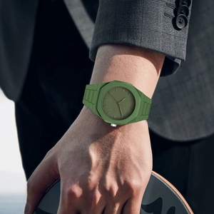 Army green sports watch with integrated silicone strap worn by a man holding a skateboard