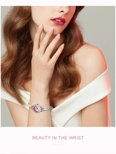 Détail d'une montre femme avec cadran rose, index en cristal et bracelet jonc argenté
