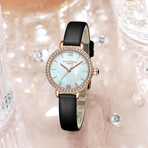Montre femme en or rose avec lunette diamantée et bracelet en cuir noir sur fond rose