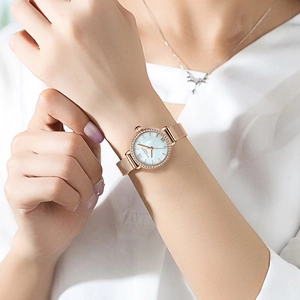 Montre élégante en or rose pour femme avec lunette sertie et cadran nacre bleu