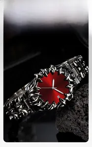 Close-up of gothic demon eye watch featuring red sunburst dial and metal claw carving