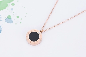 Macro du pendentif de collier en or rose avec centre noir et gravure latérale