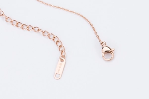 Vue macro du fermoir collier or rose avec chaîne ajustable et gravure diamant de 0,006ct