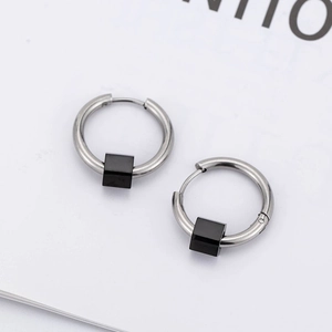 Boucles d'oreilles créoles en acier argenté avec pendentifs cubes noirs sur fond blanc