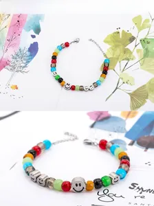 Dettaglio macro di perle di vetro colorate e ciondoli smiley su un bracciale in acciaio