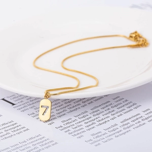 Lucky number 7 oval pendant necklace in gold stainless steel on a white ceramic plate