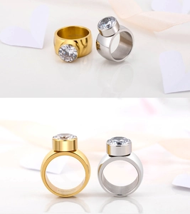 Detalle de anillos anchos de acero dorado y plateado con gran circón redondo brillante