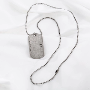 Vintage industrial style stainless steel dog tag necklace on white fabric background