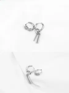 Macro view of asymmetrical silver titanium steel earrings with geometric rod pendants