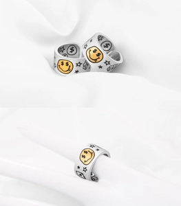 Detailed view of silver hip-hop rings with yellow smiley faces and graffiti patterns