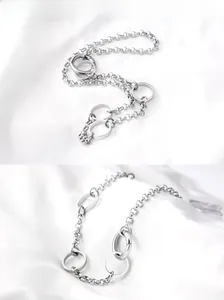 Detail view of punk style stainless steel chain necklace on white silk fabric background