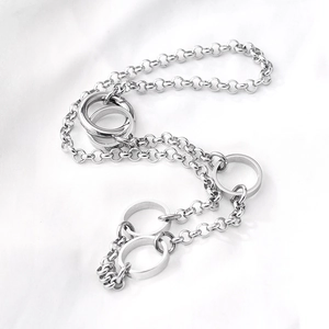 Punk style stainless steel O-chain necklace with multiple ring pendants on white fabric